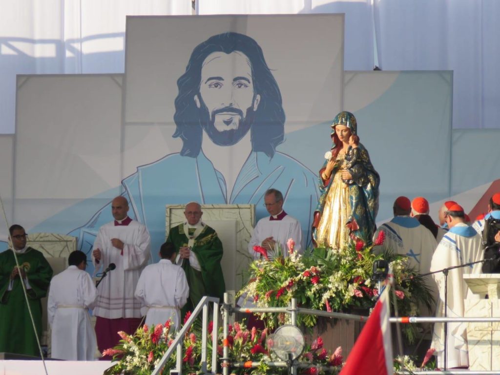 Papa Francisco em frente ao altar com a imagem de Jesus ao fundo e de Maria ao lado direito.